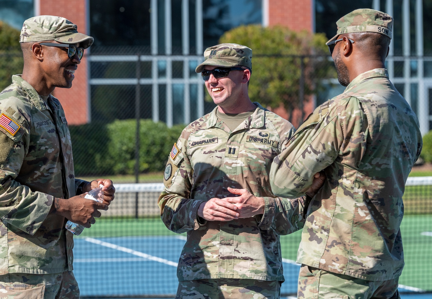 Three soldiers chatt at the FSU tennis courts.