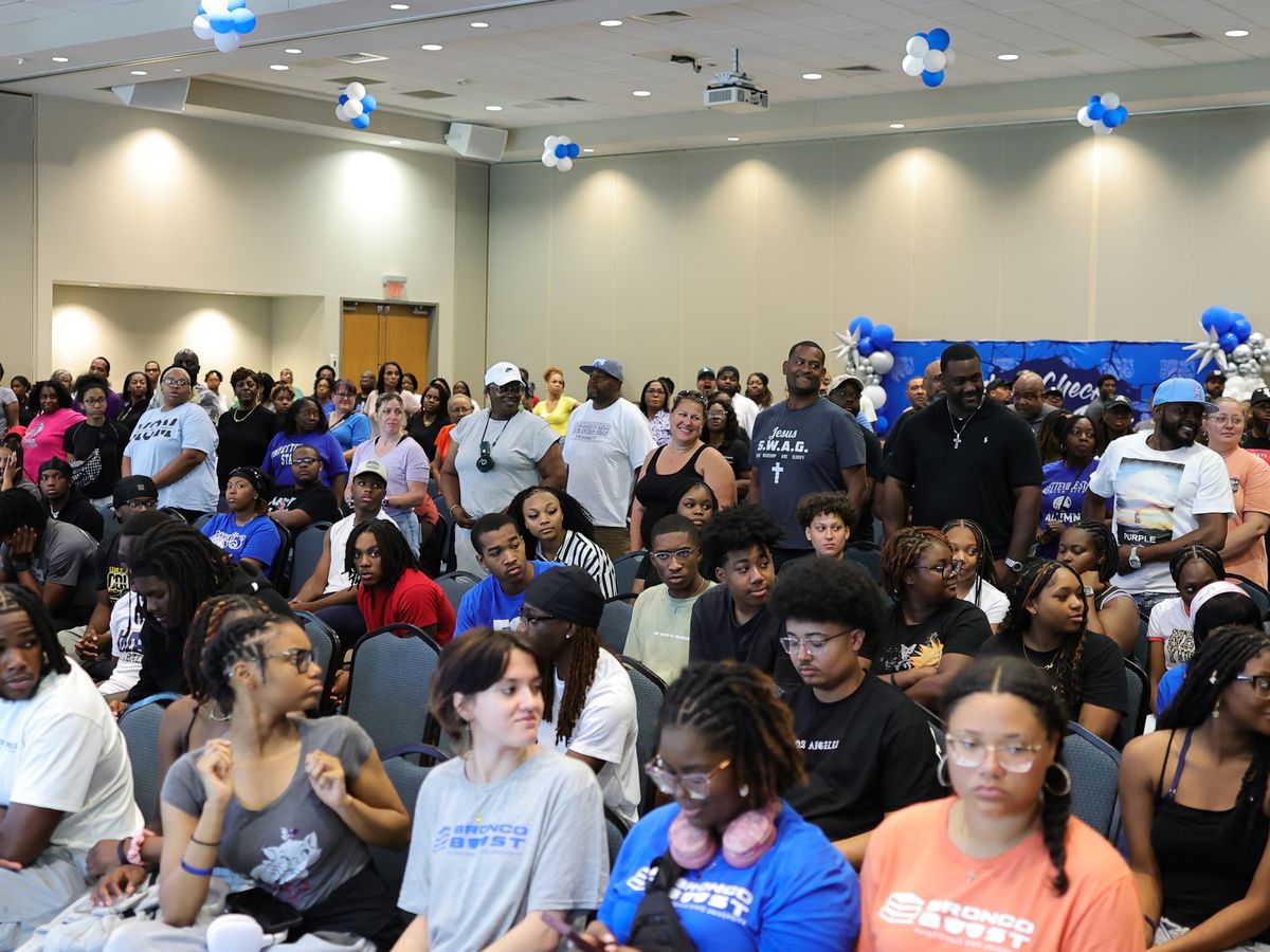A full ballroom of students and families at an FSU Bronco Boost event, with blue and white balloons and an Attitude Check, Bronco Pride backdrop