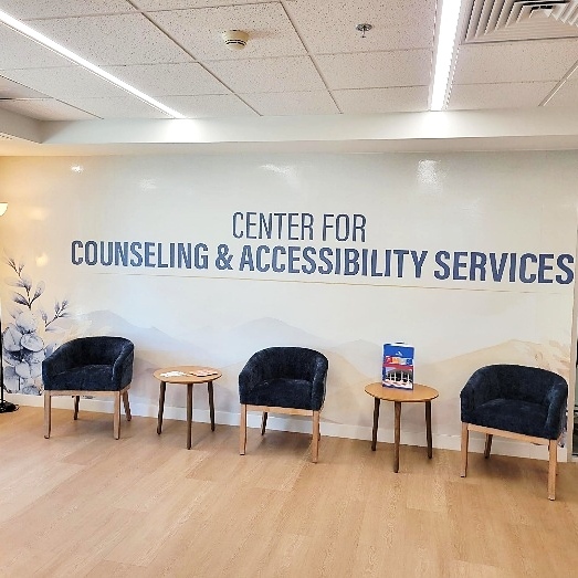 Chairs in a waiting room, a sign reads: Center For Counseling & Accessibility Services