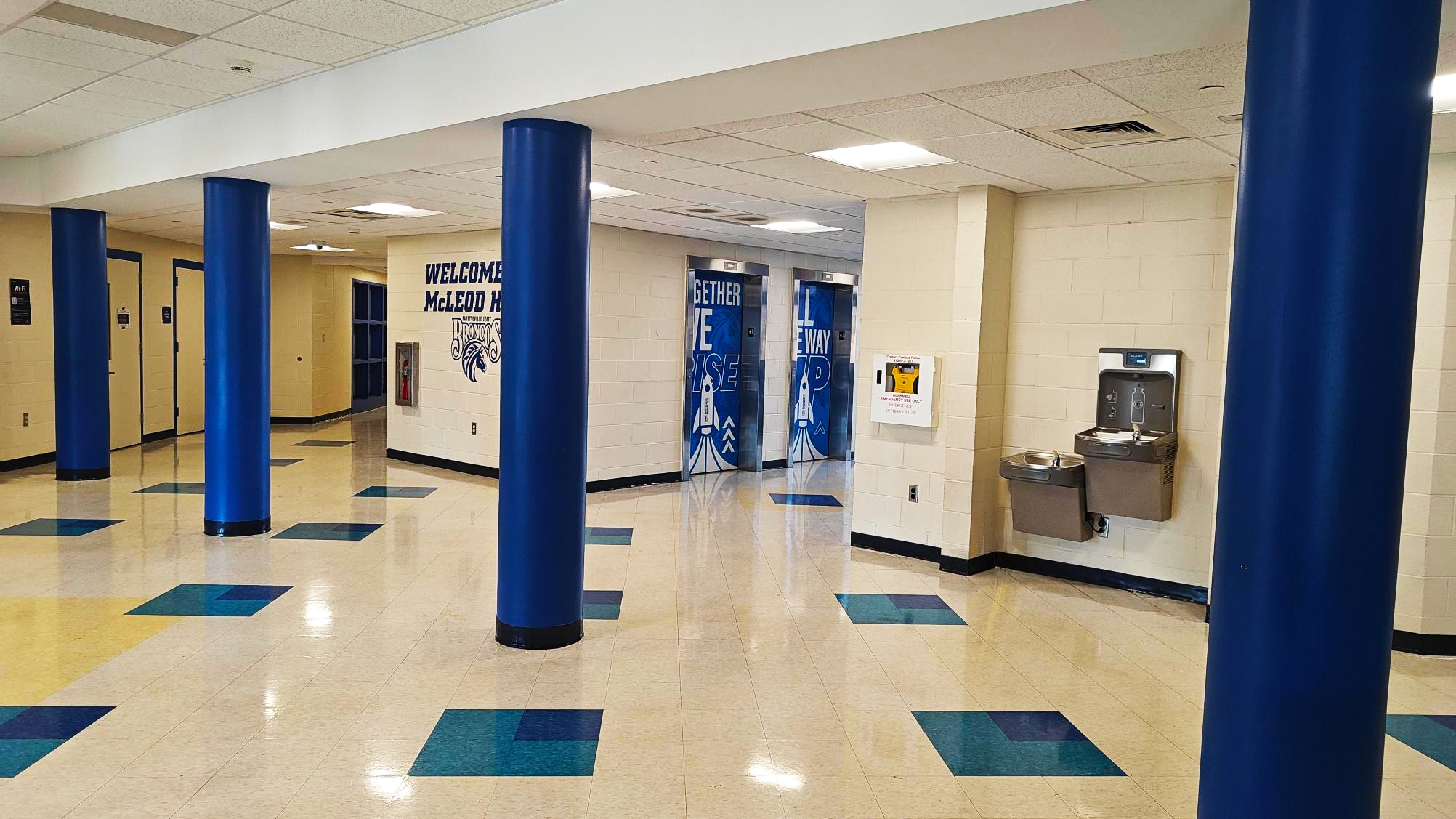 An offwhite hallway with blue pillars.