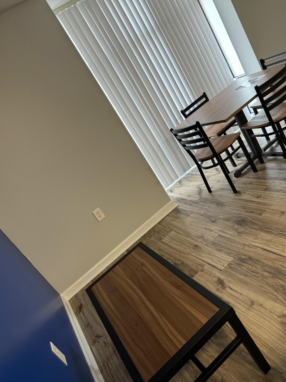 An angled shot of a sining room table, frammed by a floor length window.