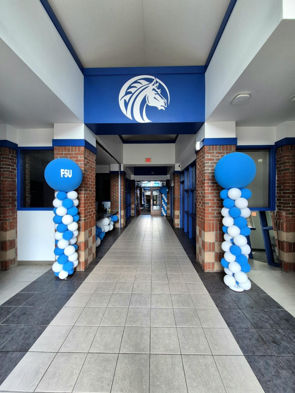 A sharp hallways decorated with blue and white balloons.