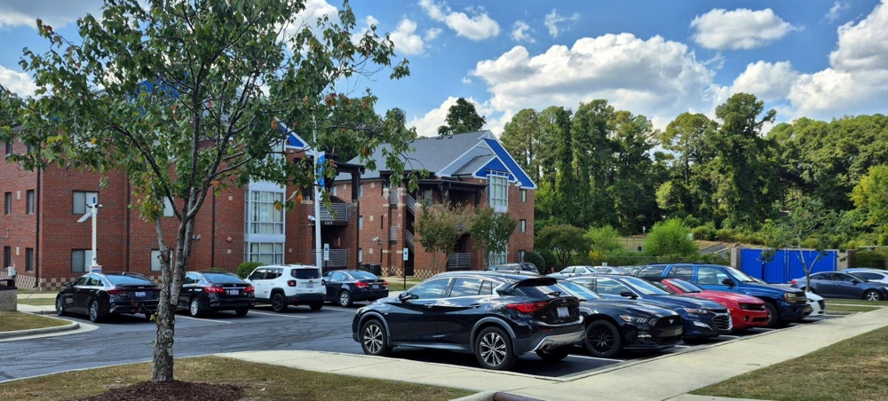 Two of the brick apartment buildings, with a wide angle view of parking.