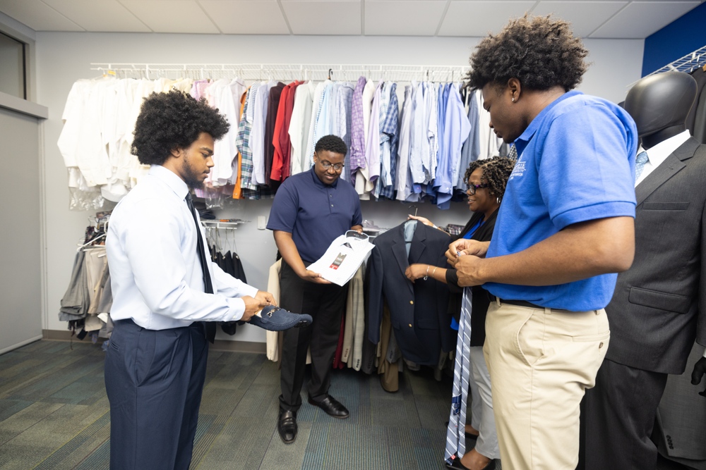 Nigel, amonst a group of students handling garments.