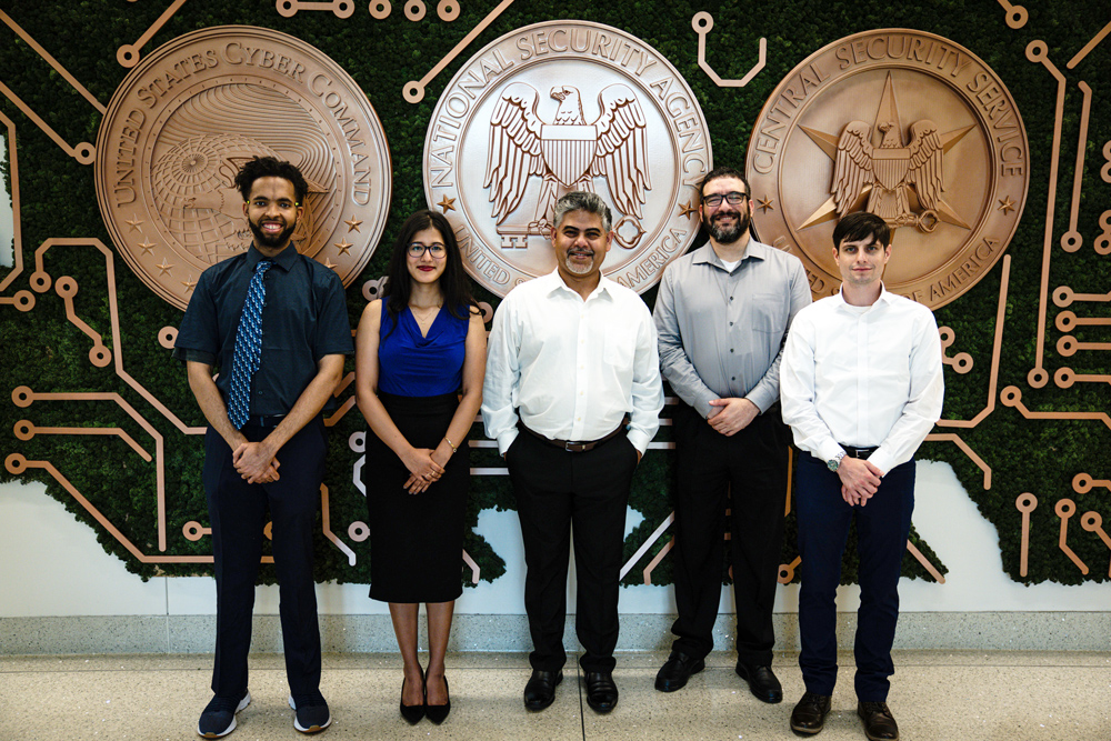 Faculty and students facing a camera, in a NSA facility.