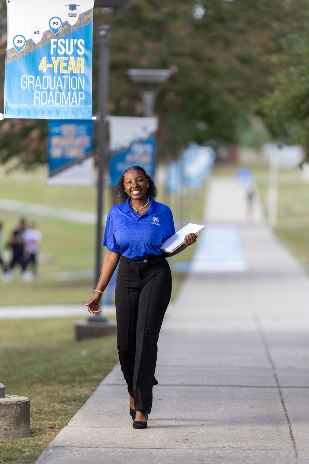 A sign reading: FSU's 4-year Graduation Roadmap; a smiling student walks beneath.