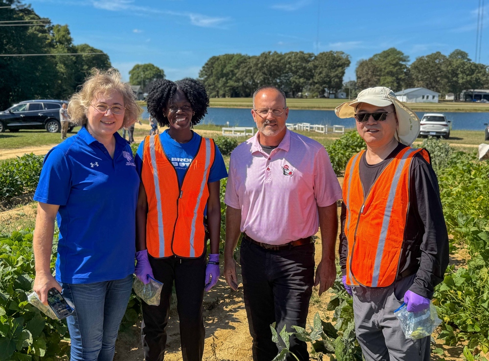 Faculty standing in front of a field of soybeans.