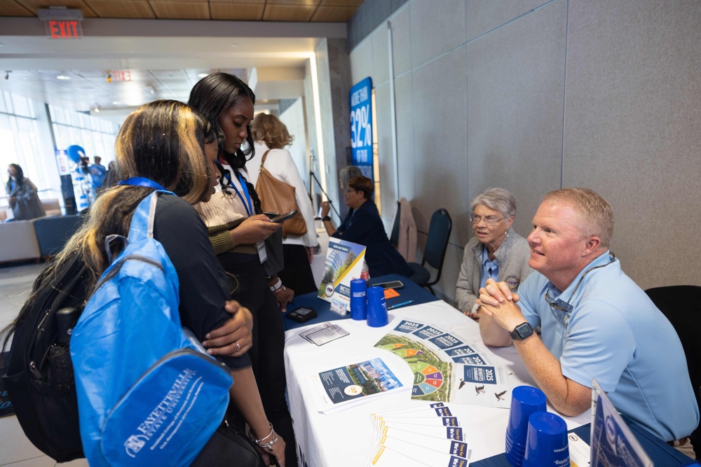 Students and staff gathered around a table.