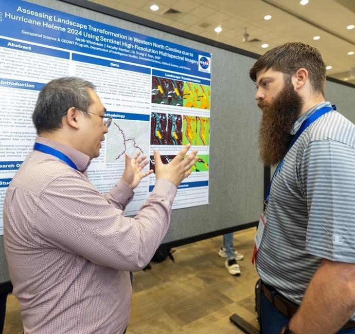 Two gentlemen discussing in front of a presentation.