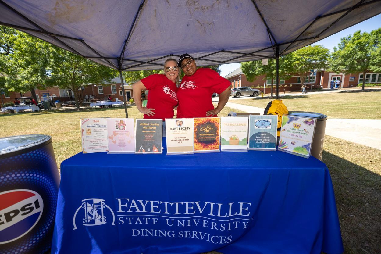 Two dining services staff underneath a tent