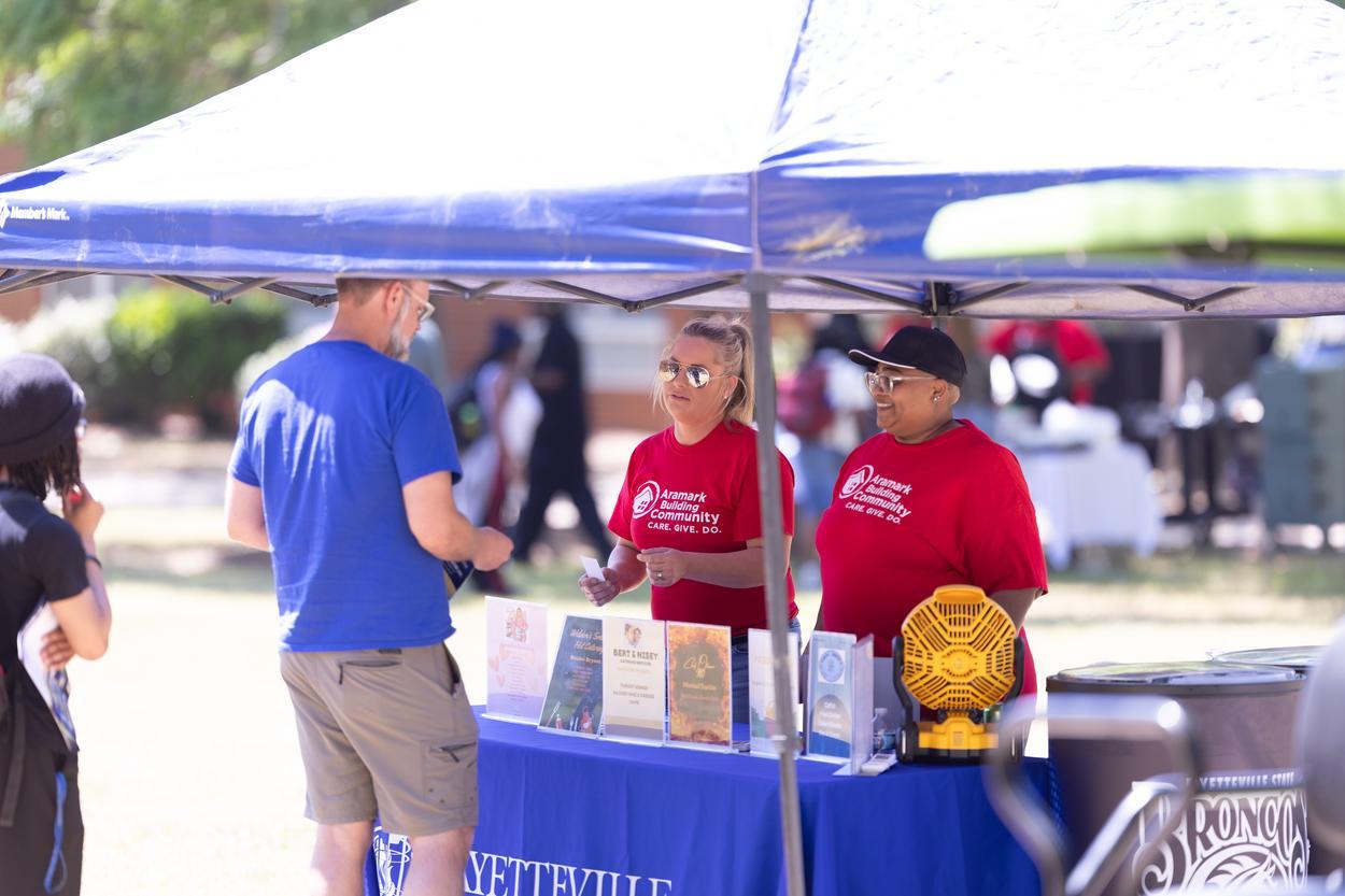 Staff members at a tent greeting students and guests.