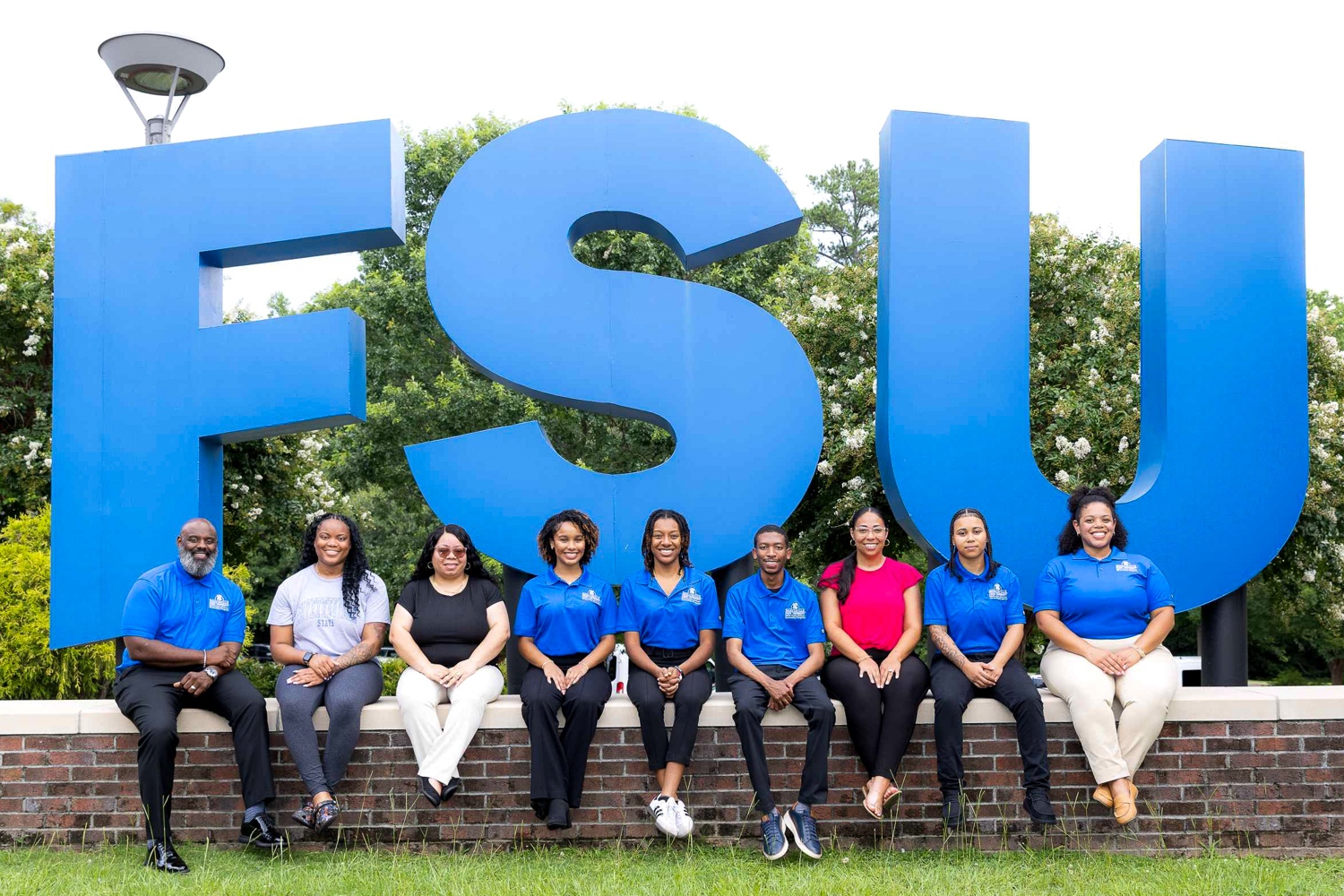 SECU Public Fellos members, smiling in front of a large F.S.U. sign.