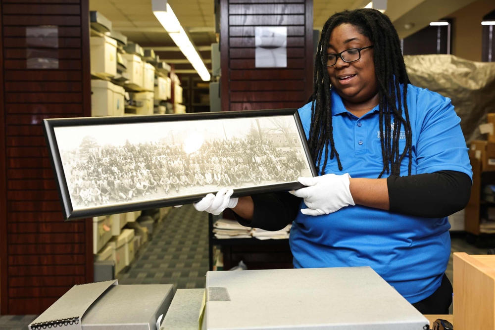 Nicholle Young St. Leone, holding a black and white photo with white gloves.
