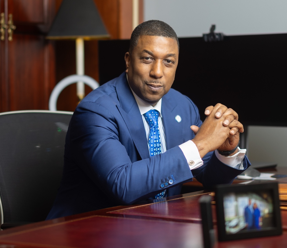 Chancellor Allison at his desk, his hands clasped.