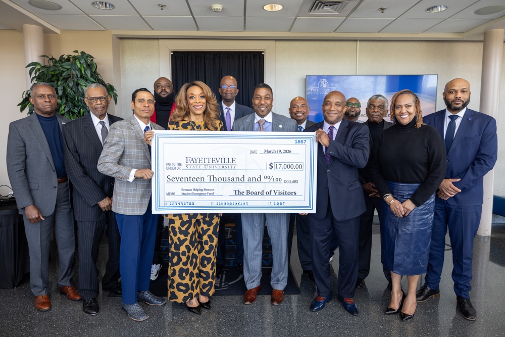 The chancellor and the Board of Visitors standing with a novelty check.