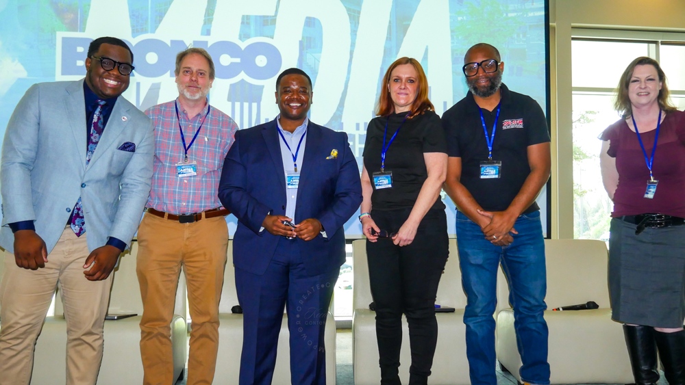 A number of individuals standing and smiling at the camera.