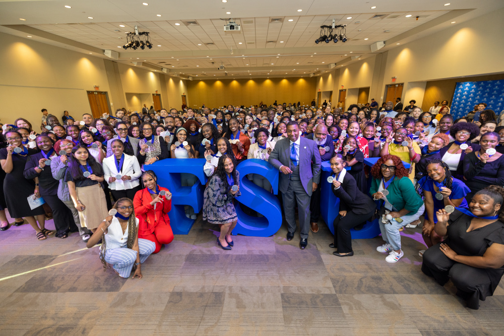 A crowd of students standing around the chancellor smiling.