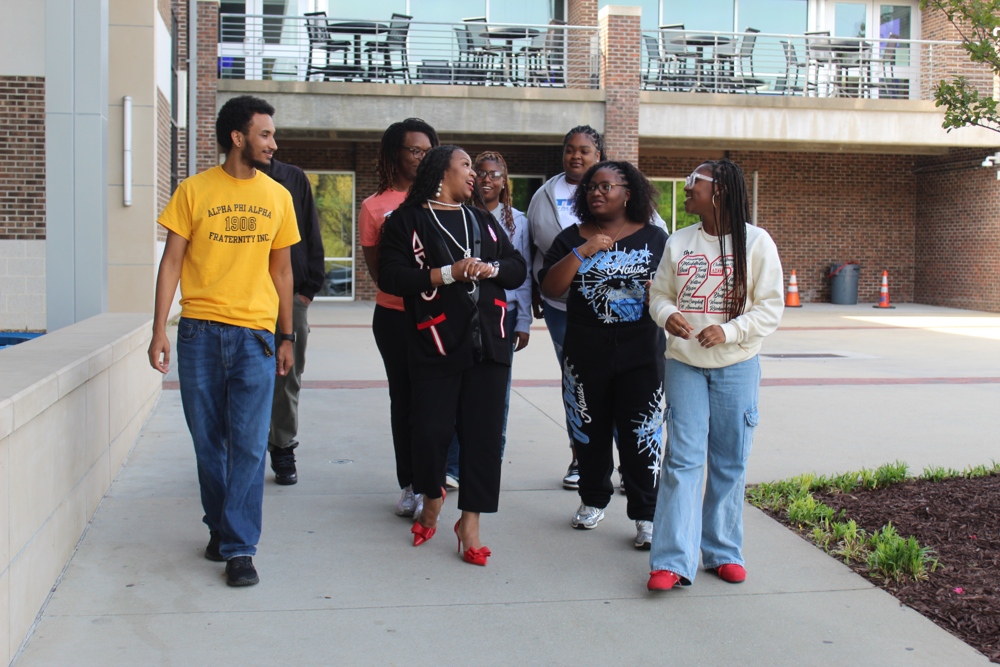 SeQuenna walking through a concrete courtyard with a number of students.