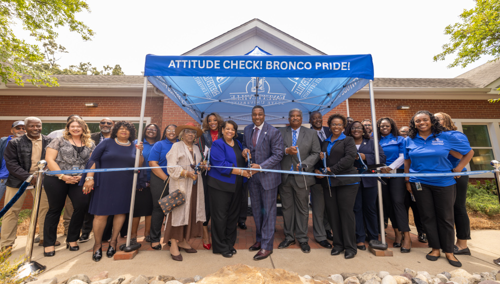 The chancelor with a crowd, cutting a ribbon. 