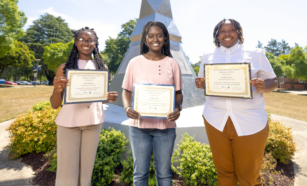 Mia Danielle Thompson, Sokhna Amar, and Shereiff Garrett smiling outside, holding certificates.