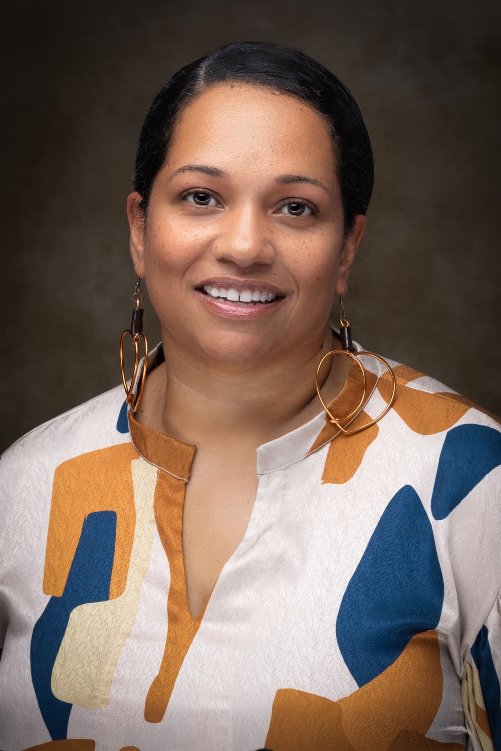A smaling woman, with a multicolored blouse.