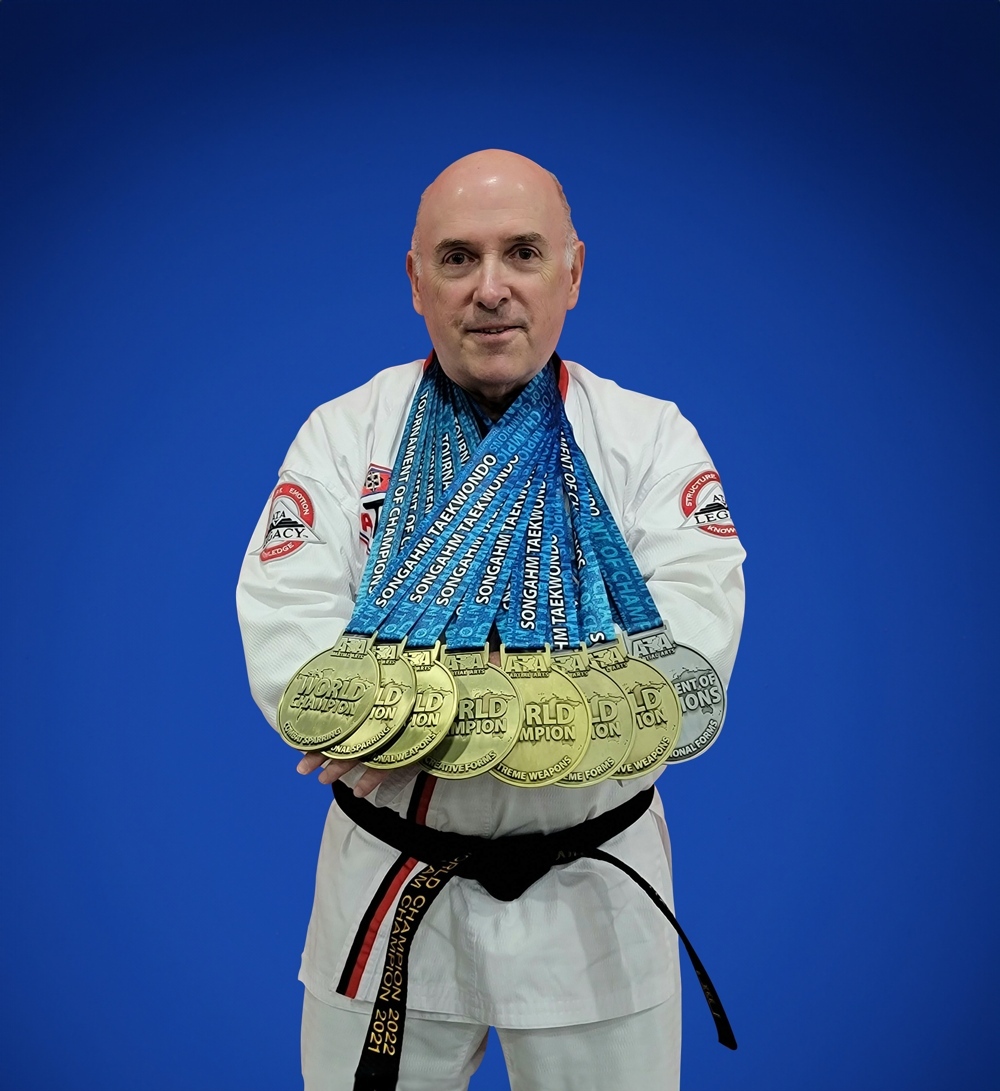 Dr. McGee in full Taekwondo attire, with seven gold medals around his neck.