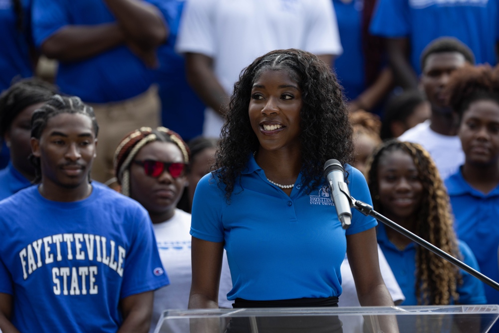 A woman in a blue shirt standing behind a podium.