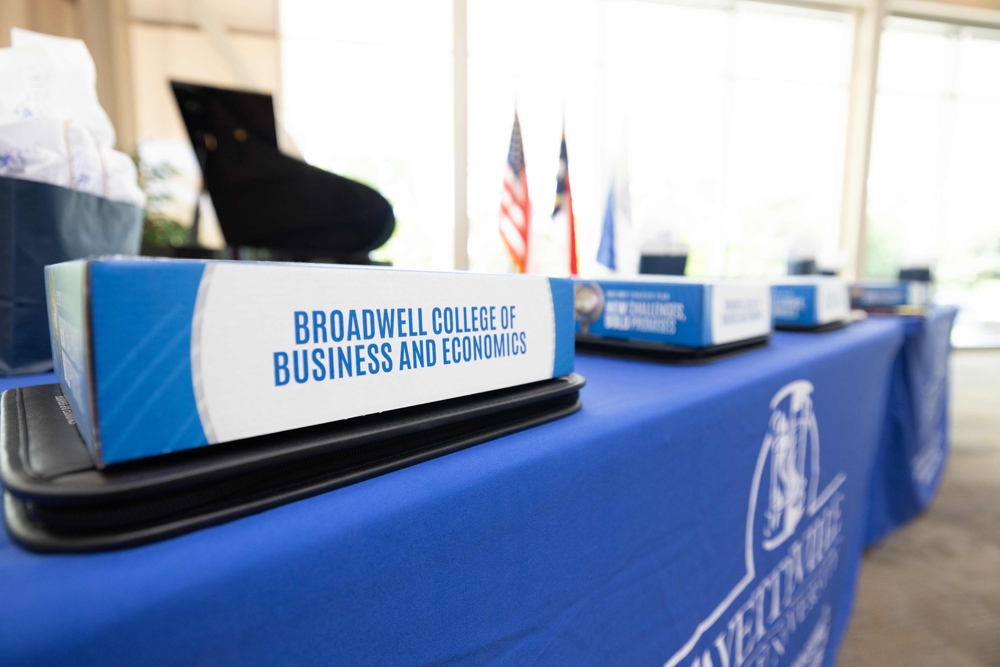 A short blue and white sign atop a table reads: Broadwell College of Business and Economics