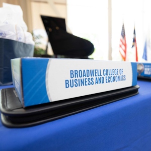 A short blue and white sign atop a table reads: Broadwell College of Business and Economics.