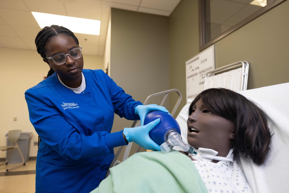A nursing student tending to a medical test dummy.