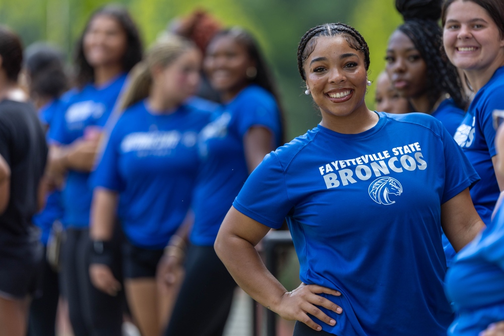 A number of students in a crowd smiling and wearing blue FSU shirts.