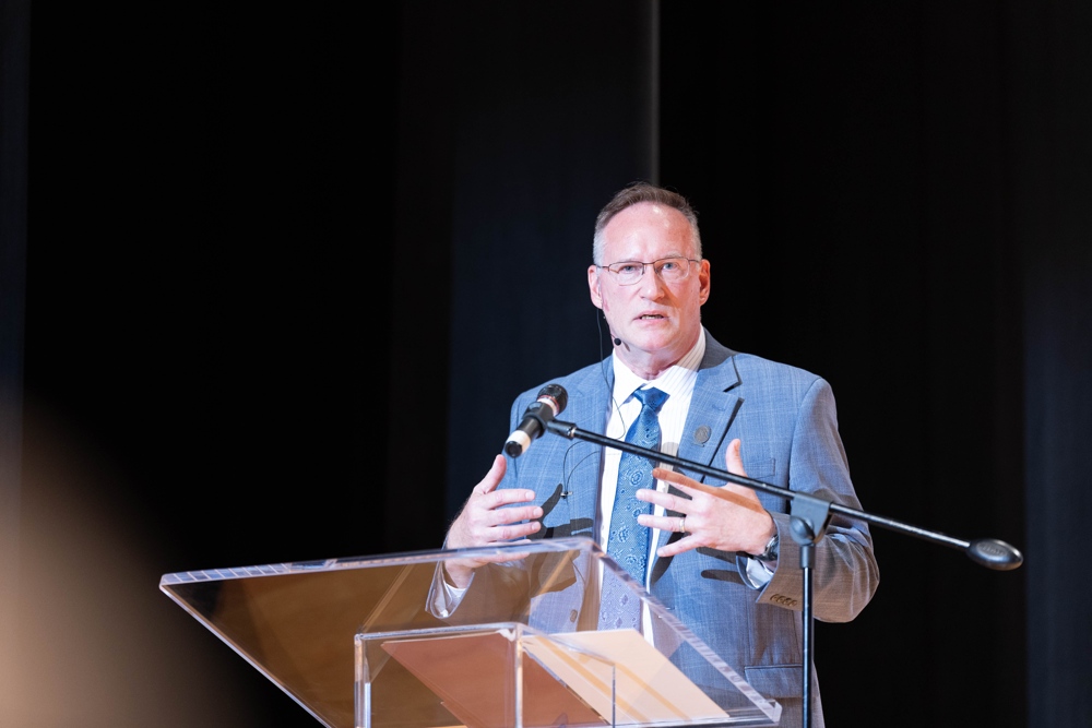 A distinguished man in a blue suit at a pdoium.