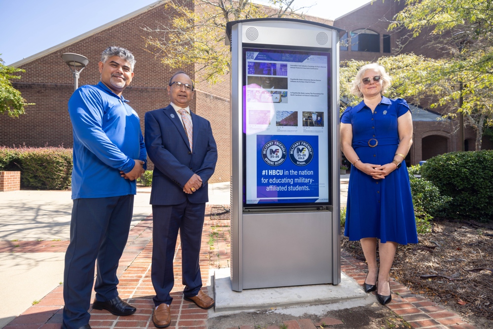Three FSU Faculty standing before an electronic sign.