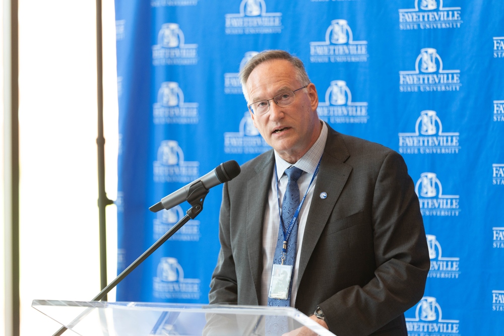 The Provost standing in front of a blue backdrop.
