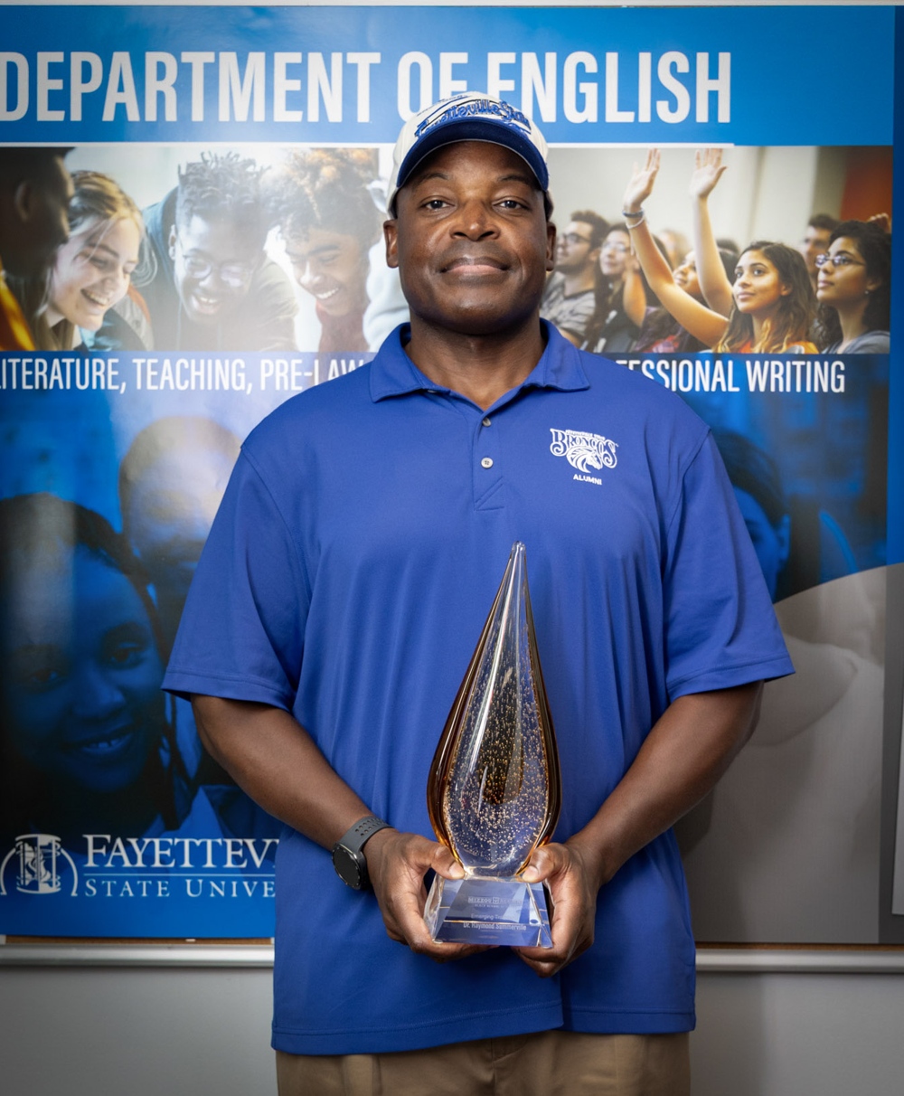 A man in FSU blue proudly holding an award.