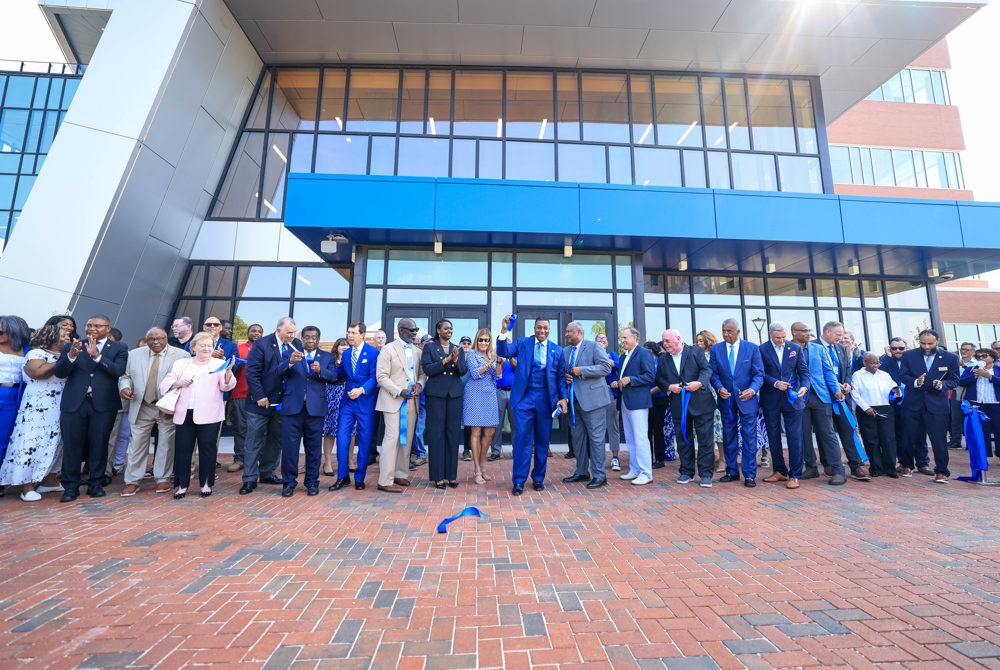 A crowd at a ribbon-cutting ceremony. The Chancelor holding the ribbon.