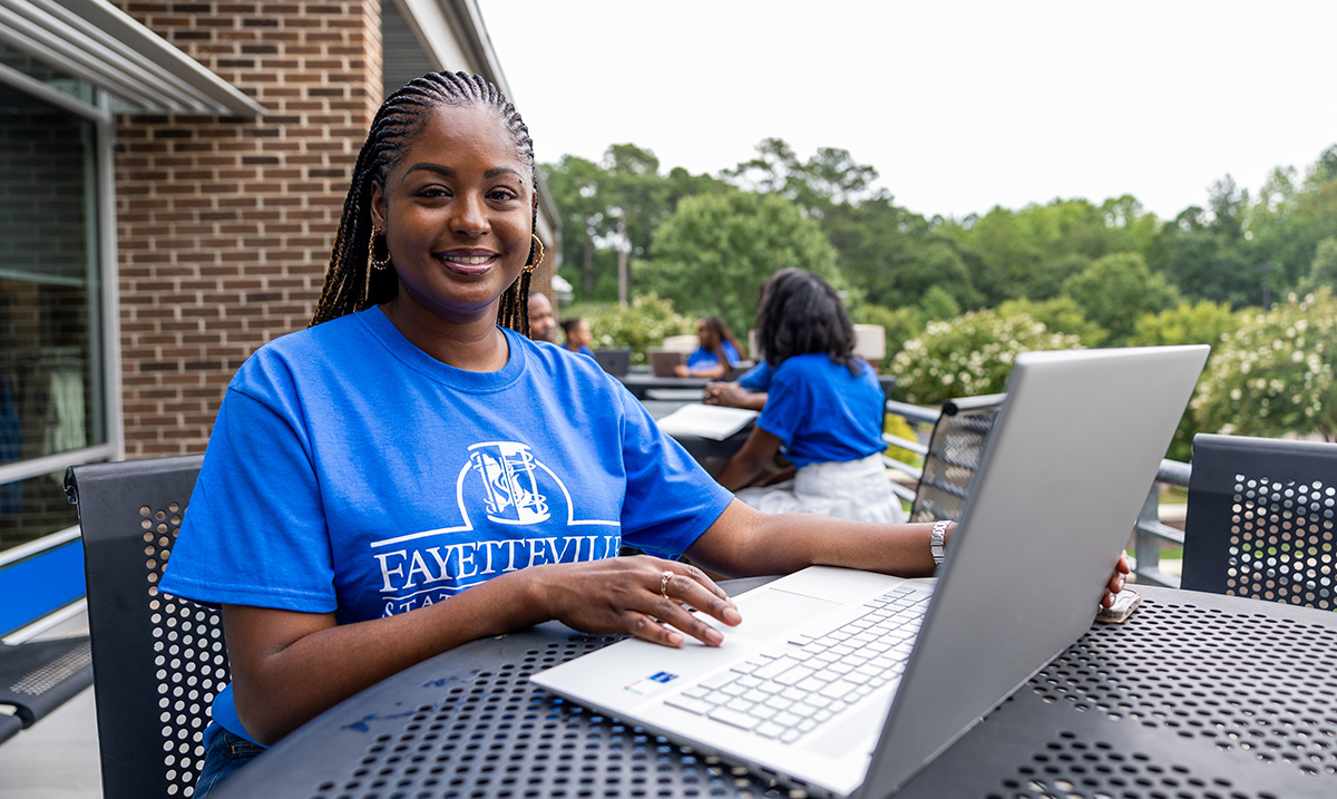 Person Using A Laptop Wearing a Fayetteville State Shirt