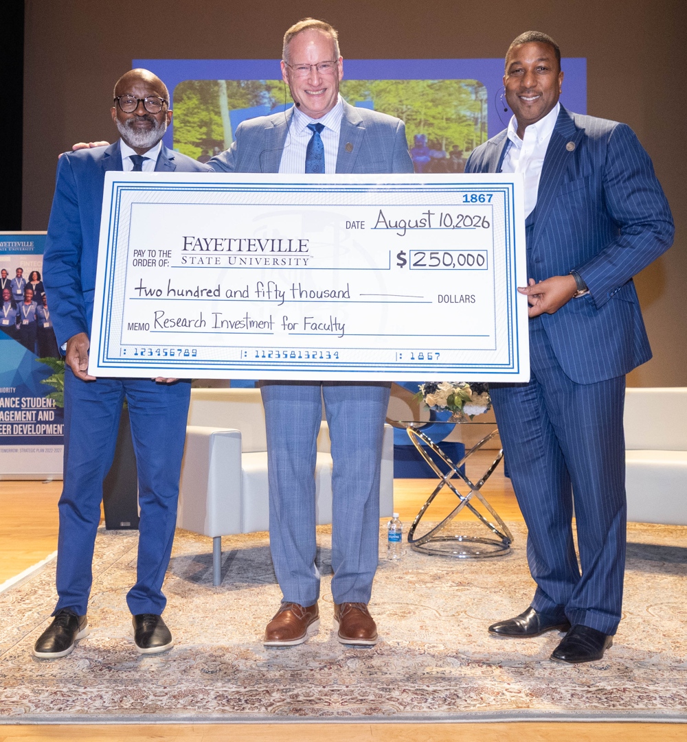 Three men proudly displaying a novelty check.