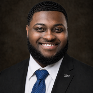 Headshot of Jah-Mes Coley in a blue tie.
