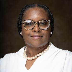 A woman smiling, with glasses and a white blouse.
