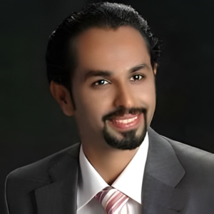 A bearded man smiling in a grey suite.