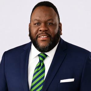 Dr. Terence McCrimmon in a blue suit with a green striped tie.